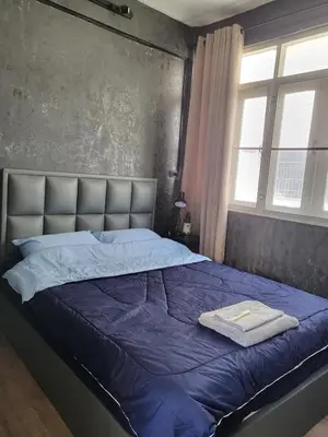 a bedroom with a bed with a blue comforter and two windows at auntythong house in Bangkok