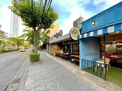 a blue building with tables and chairs on a street at 3A-168 House Near BTS-icon siam in Godown