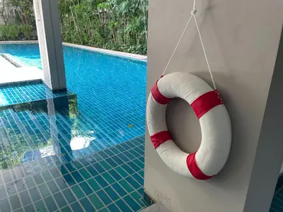 a swimming pool with a red and white life ring next to a swimming pool at Delight Home in Amphoe Phra Khanong