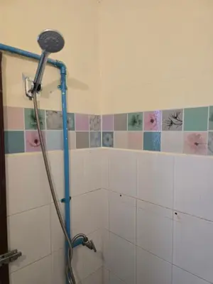 a shower head in a bathroom with a tiled wall at J Place Studio 204 with nice fan free Wifi, near Skytrain in Bangkok