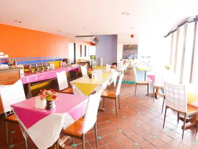 a restaurant with tables and chairs with pink and yellow at Best Comfort Bangkok Hotel in Bangkok