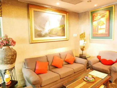 a living room with a couch and orange pillows at Best Comfort Bangkok Hotel in Bangkok