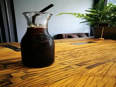 a glass bottle sitting on top of a wooden table at sook station in Bangkok