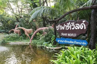 a sign in a garden with giraffes by a river at 5BOX Donmuang Airport in Bangkok