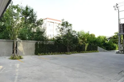 an empty parking lot with a building in the background at Home Inn Hotel in Bangkok