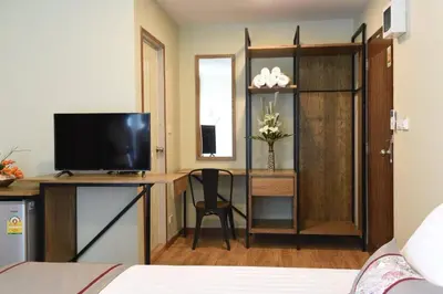 a bedroom with a bed and a desk with a television at Home Inn Hotel in Bangkok