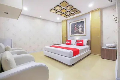 a bedroom with a large bed and two chairs at OYO 1002 Pinklao Resort in Bangkok