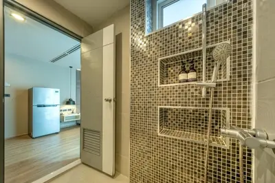 a bathroom with a shower with a tile wall at Ralph Poshtel Pratunam in Bangkok