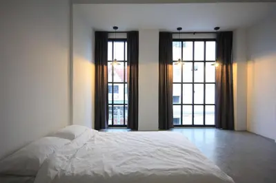 a bedroom with a white bed and two windows at L22 HOSTEL in Ban Khlong Samrong