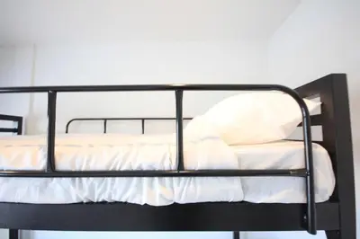 a black bunk bed with white sheets and a pillow at L22 HOSTEL in Ban Khlong Samrong