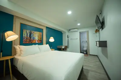 a bedroom with a large white bed and a blue wall at SkyLink Homes - Pattunaam - Airport Link & BTS Chidlom in Bangkok