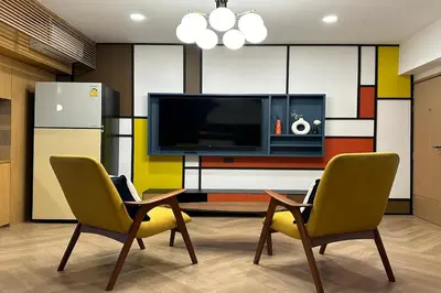 a living room with two chairs and a television at Parcel Hotel Bangkok in Bangkok
