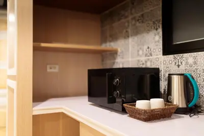 a microwave on a counter in a kitchen at Rere Hostel - รีรีโฮสเทล in Bangkok