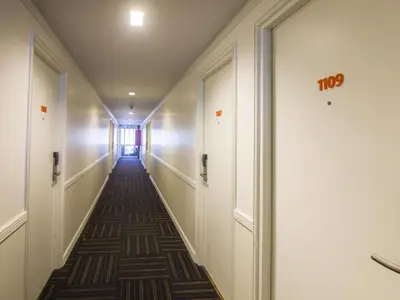 a corridor in a building with white walls and a long hallway at First House Hotel in Bangkok