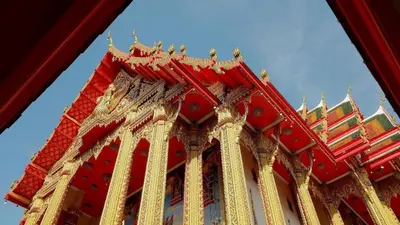 a red and gold building with a blue sky in the background at Super Hostel in Nonthaburi