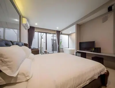 a bedroom with a large white bed and a television at The Valen Resort in Bangkok