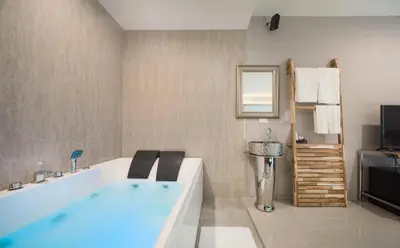 a bathroom with a bath tub and a television at The Valen Resort in Bangkok