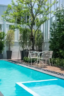 two chairs and a table next to a swimming pool at Hostel De Kaya in Bangkok