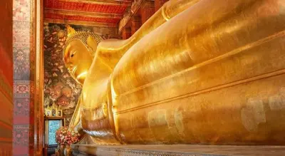 a gold statue in a room with a painting at Hostel De Kaya in Bangkok