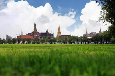 a green field with a building in the background at Hostel De Kaya in Bangkok