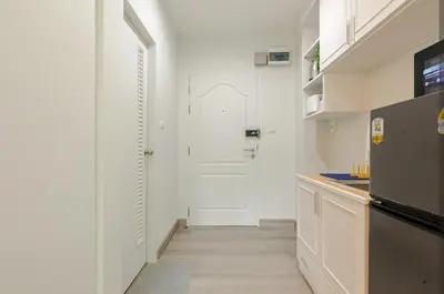 a kitchen with white walls and a white door at Sense of London BTS Baring in Ban Khlong Samrong