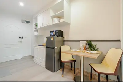 a kitchen with a small table and a refrigerator at Sense of London BTS Baring in Ban Khlong Samrong