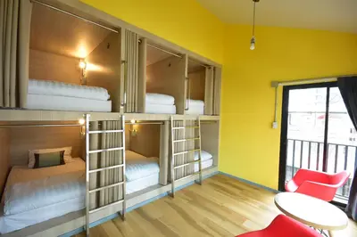 a room with bunk beds with a table and chairs at Bangkok Silom chat box hostel in Bangkok