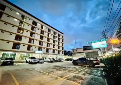 a large building with cars parked in a parking lot at Nicha Residence Hotel in Bangkok
