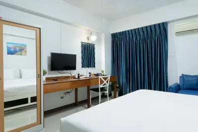 a bedroom with a desk and a bed and a television at Nicha Residence Hotel in Bangkok