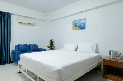 a bedroom with a white bed and a blue couch at Nicha Residence Hotel in Bangkok