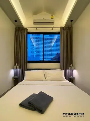 a bedroom with a white bed with a window at Monomer Hostel Bangkok in Bangkok