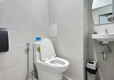 a white bathroom with a toilet and a sink at Center at Bangrak in Bangkok