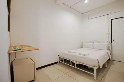 a white bedroom with a bed and a table at XX GO INN Asiatique Charoen krung V โกอินน์ เอเซียทีค เจริญกรุง in Bangkok