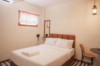 a bedroom with a white bed with a chair and a table at JB Home Bangkok - Victory monument in Bangkok
