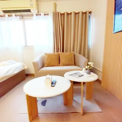 a living room with a couch and two tables at NK hostel 18 in Thung Si Kan