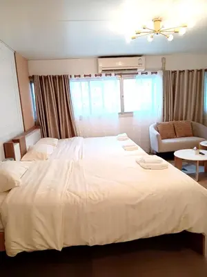 a bedroom with a large white bed and a couch at NK hostel 18 in Thung Si Kan