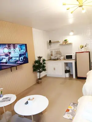 a living room with two tables and a tv on the wall at NK hostel 18 in Thung Si Kan