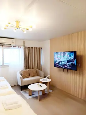 a living room with a couch and a tv on a wall at NK hostel 18 in Thung Si Kan