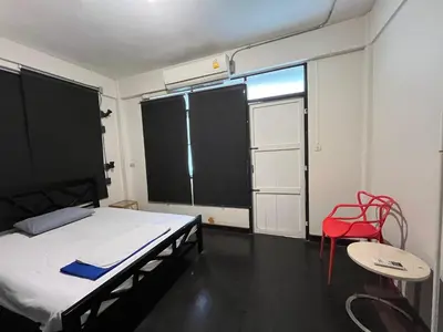 a room with a bed and a red chair and a window at silom Dream catcher rainbow hostel in Bangkok
