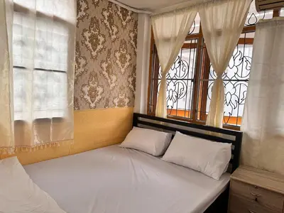 a bed with two pillows in a room with windows at Yuma Tashi Hostel in Bangkok