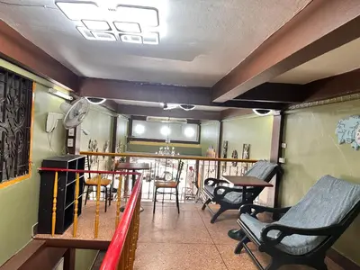a balcony with chairs and a table and a bar at Yuma Tashi Hostel in Bangkok