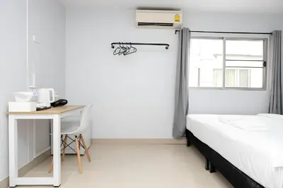a bedroom with a bed and a desk and a window at Elite Hotel Nana Sukhumvit 3 in Bangkok