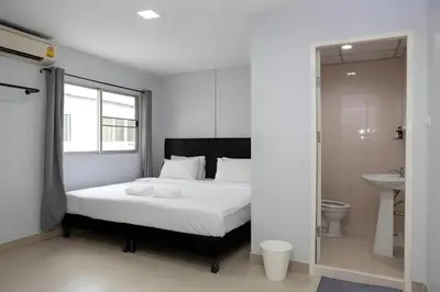 a bedroom with a white bed and a bathroom at Elite Hotel Nana Sukhumvit 3 in Bangkok