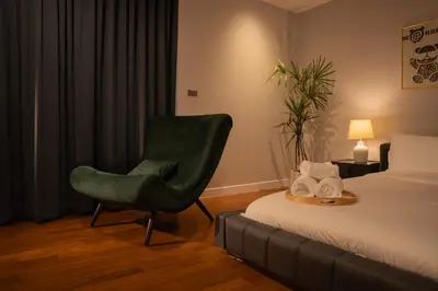 a hotel room with a green chair next to a bed at 943summer villa曼谷中心Asok&Tong lor800平海天别墅 in Bangkok