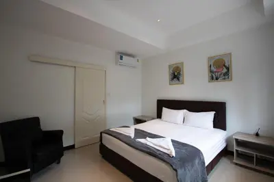 a bedroom with a bed and a black chair at Arttra Villa in Bang Chak