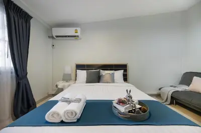 a bedroom with a bed with towels and a couch at 4BR house MRT subway 250m Chatujak Market wi-fi in Bangkok