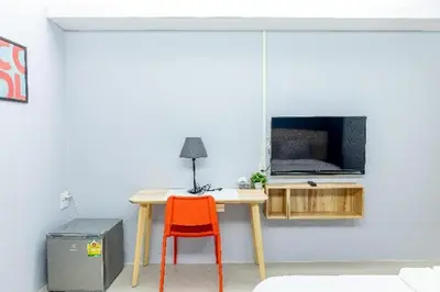 a table with a orange chair in a room with a tv at Your Place Hotel in Bangkok