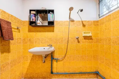 a yellow tiled bathroom with a sink and a shower at Sleepinn Bang Chak in Bangkok