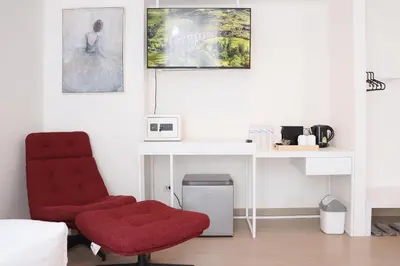 a room with a red chair and a desk at ResT Bangkok Poshtel in Bangkok