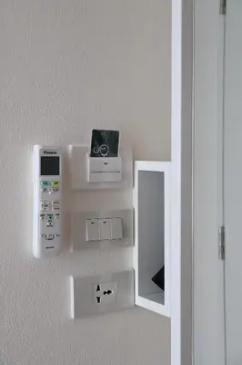 a wall with a mirror and a device on a wall at ResT Bangkok Poshtel in Bangkok